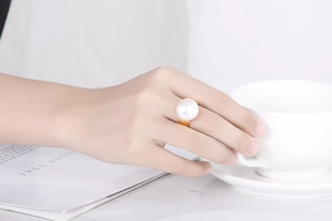 Chic gold-plated wide band ring featuring a large white pearl on a model hand