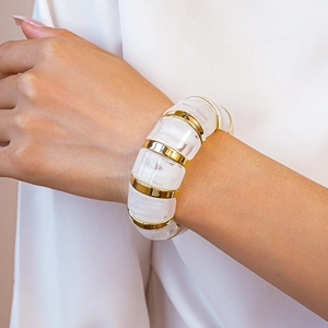 Detail of geometric acrylic bangle featuring white resin segments and gold metal accents