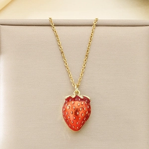 Macro detail of a 3D red strawberry enamel pendant on a delicate gold titanium steel chain