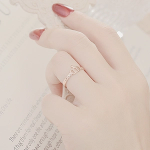 Detail of rose gold crown ring on hand with elegant red nails and magazine background