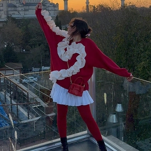 Détail d'un sweat rouge avec un grand motif de cœur à volants blancs sur un toit urbain