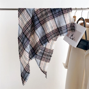 Detail view of multicolored plaid scarf with tassels hanging naturally in a lifestyle setting