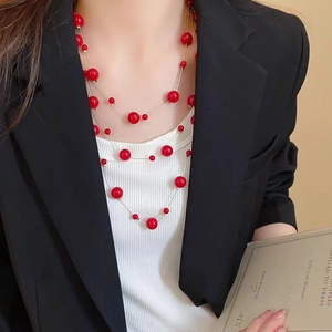 Detailed close-up of a three-layer gold chain necklace with vibrant red bead accents