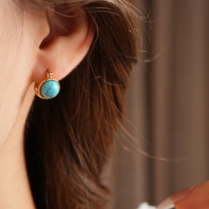 Gros plan d'une boucle d'oreille vintage en résine turquoise et cadre doré