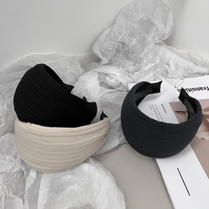 Close-up of stylish wide headbands in black, beige, and grey with pleated textures