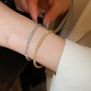Détail de bracelets minimalistes en or et argent avec finition sablée scintillante