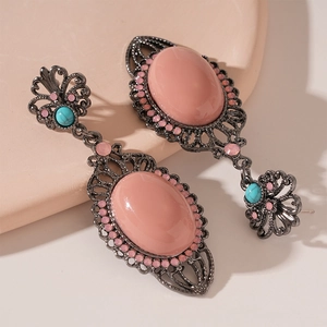 Close-up of bohemian floral drop earrings with pink resin stone and turquoise beads