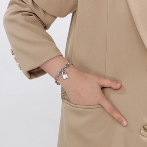 Close-up of a silver stainless steel chain bracelet with a metal lock pendant on wrist