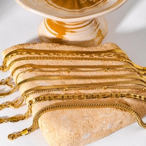 Set of gold stainless steel multi-style chain bracelets displayed on natural stone