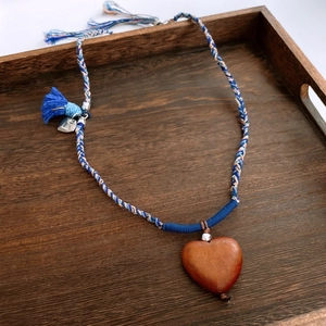 Detailed macro of the woven cotton rope and heart-shaped wooden pendant necklace
