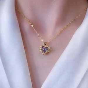 Detail of titanium heart necklace with purple crystal pendant on golden chain
