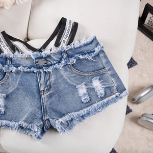 Dettaglio di pantaloncini di jeans blu con bordi sfrangiati e nastro stampato bianco e nero