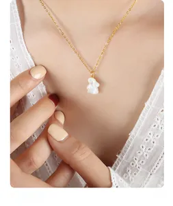 Gros plan d'un collier doré avec pendentif lapin blanc mignon sur le décolleté