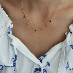 Macro view of double-layered gold-plated necklace with blue beads and small gold pendants