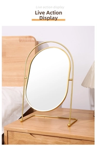 Detail of oval desktop makeup mirror with golden metal frame and top handle design