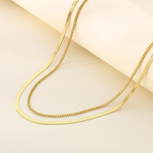Detail of gold double-layered necklace with flat snake chain and Cuban link design