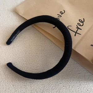 Detail of a thick black knitted headband featuring a handmade label on the inner side