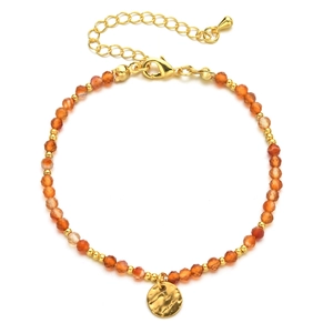 Detail of beaded bracelet with orange faceted stones, gold spacers, and hammered pendant