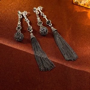 Vintage silver tassel earrings with black rhinestones on a textured brown background