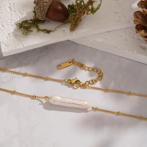 Detailed close-up of a baroque pearl necklace with a gold chain and S.STEEL engraving