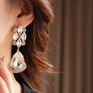 Close-up of vintage gold rhombic drop earrings with rhinestones on a female model