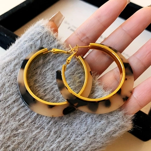 Détails de boucles d'oreilles créoles en résine écaille de tortue et bordure dorée