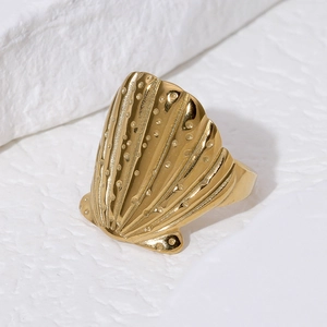 Minimalist gold shell-shaped stainless steel ring with wave texture on stone background
