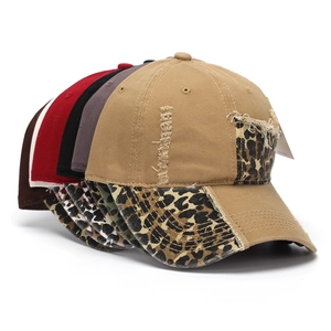 Close-up of distressed baseball caps featuring leopard print patchwork and ripped details