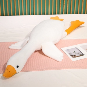Detail of soft white goose plush pillow with bright orange beak on a cozy bed setup