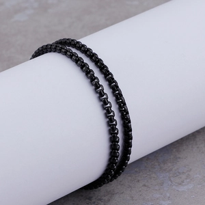 Close-up of black metal link chain bracelet wrapped around a white cylindrical stand