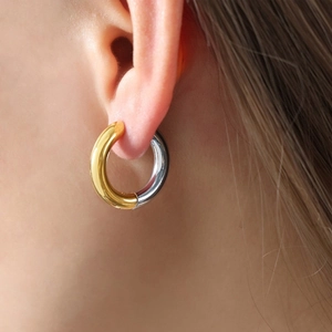 Close-up of two-tone gold and silver titanium steel hoop earrings on a female model