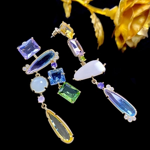 Macro shot of long drop earrings with colorful geometric gems on a gold base