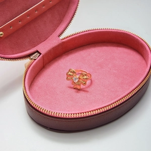 Dettaglio macro di un anello a fiocco dorato con zircone a cuore in una scatola di velluto rosa