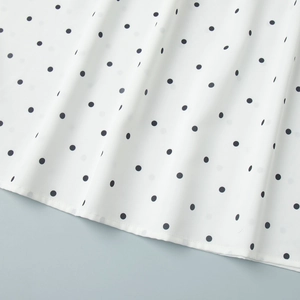 Detail shot of the hem of a white polka dot chiffon blouse with precise stitching