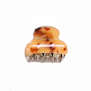 Detail view of small amber tortoiseshell hair claw clip with silver metal spring and teeth