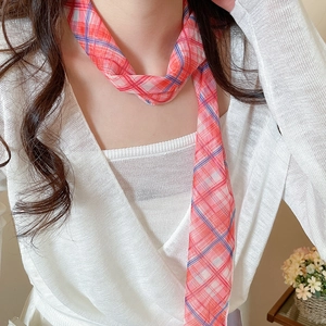 Close-up of a red plaid mesh scarf necklace worn with a white knit top