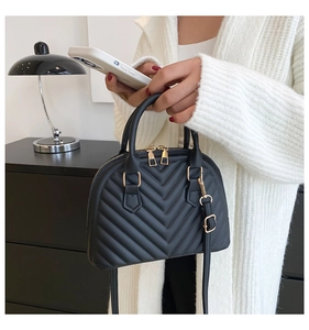 Detail of black V-quilted shell handbag with gold hardware and dual handles