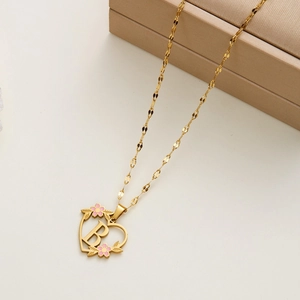Detailed macro of gold heart pendant featuring letter B and pink enamel floral accents