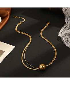 Detail of gold-plated snake chain necklace with mirror-polished gold ball pendant