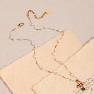Détail du pendentif croix plaqué or 18K avec zircons colorés et perles blanches délicates