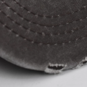 Close-up of vintage washed cotton baseball cap brim with distressed edges and triple stitching