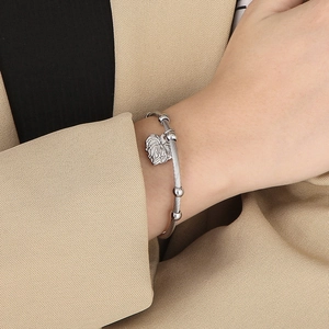 Detail of silver twisted cable cuff bracelet with heart pendant on model wrist