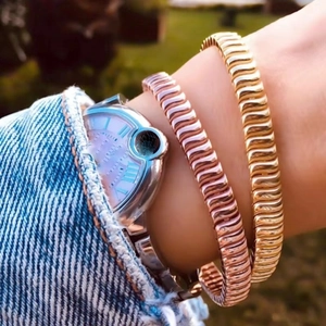 Chic 10mm gold and rose gold wavy tennis chains shown in a trendy outdoor setting