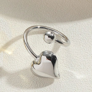 Macro detail of adjustable silver heart ring with polished ball and glossy finish
