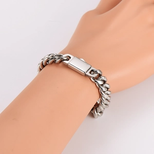 Detailed view of a silver Cuban link bracelet with a rectangle metal clasp on a wrist