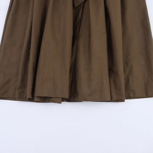 Detailed close-up of dark brown poplin fabric and double-stitched hem on the dress