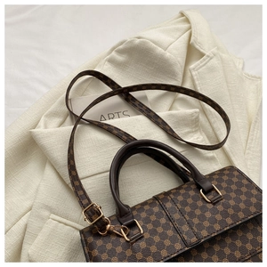 Close-up of vintage brown monogram handbag with leather handles on a tweed jacket