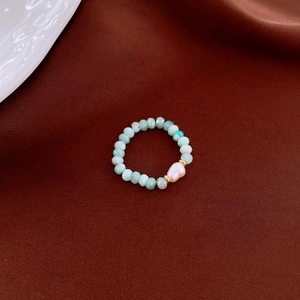 Detail of beaded ring with green amazonite stones and a white baroque pearl accent