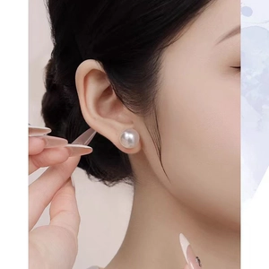 Close-up of elegant 10-12mm white pearl stud earring worn on model's earlobe