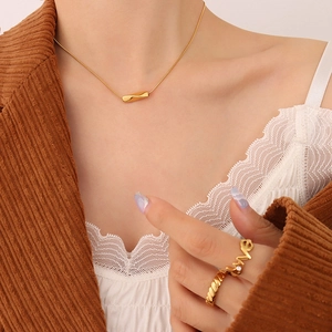 Detail view of a gold S925 silver necklace with twisted pendant and matching rings